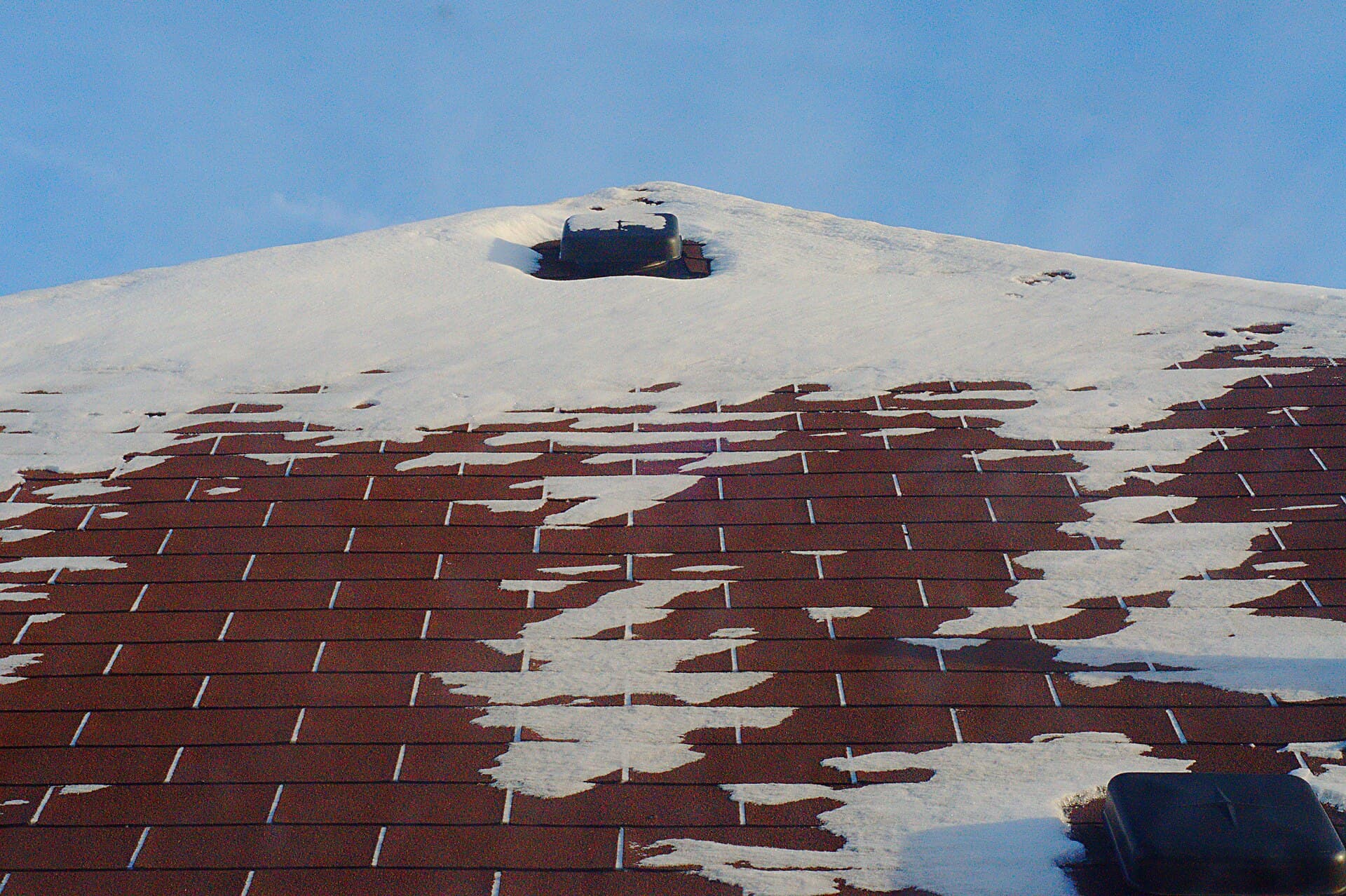 Snow melting off a red shingle roof in Mississauga, a roof vent at the ridge